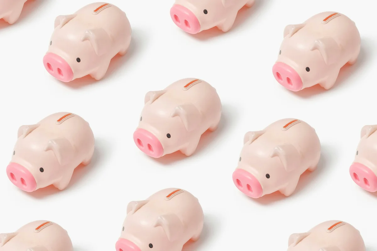 Múltiples huchas de plástico rosa organizadas sobre fondo blanco, representando el concepto de ahorro e inversión colectiva en fondos