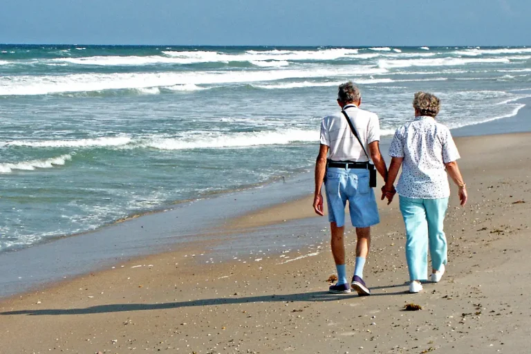 Pareja jubilada paseando de la mano por la orilla del mar, ilustrando el ahorro para la jubilación y los planes de pensiones