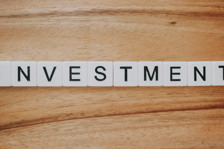 Bloques de madera con la palabra "INVESTMENT" sobre una superficie de madera, ilustrando el concepto de inversión a largo plazo en planes de pensiones.